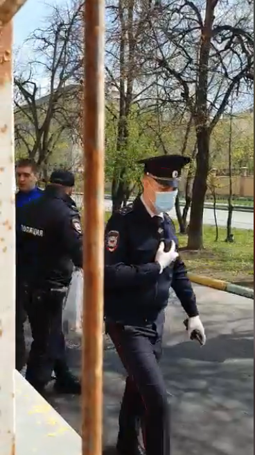 Полицейский пытается помешать передать продукты заблокированным в офисе / Скриншоты из видео Фатимы Хугаевой в фейсбуке