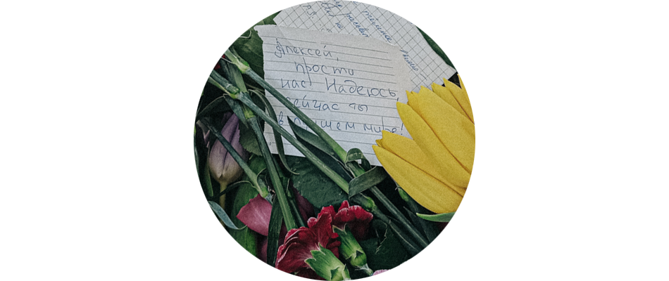 Лист бумаги с надписью «Алексей, прости нас! Надеюсь, сейчас ты в лучшем мире!» среди цветов на могиле Алексея Навального