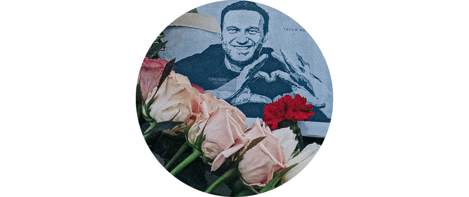 Цветы и распечатанное фото граффити с изображением Алексея Навального и надписью «Герой нашего времени» на его могиле
