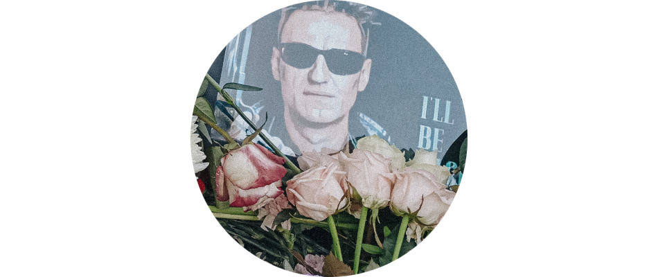 Розы и распечатанное изображение Алексея Навального в образе Арнольда Шварцнеггера, в солнечных очках и с пистолетом в руке, из фильма «Терминатор», и надписью «I'll be back» на могиле Алексея Навального